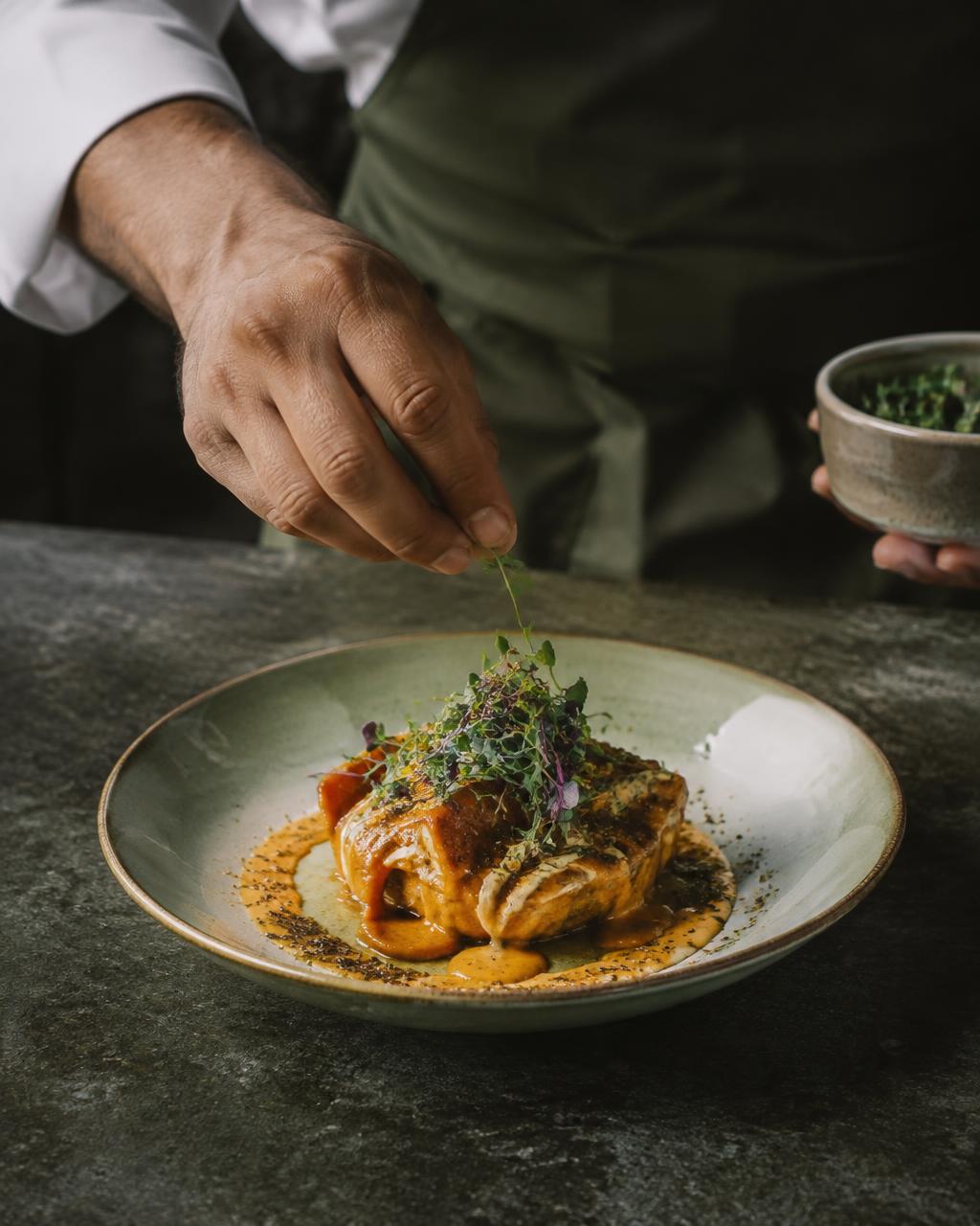 Chef garnishing a plated dish